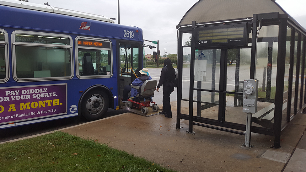 driver helps wheelchair user up ramp into bus