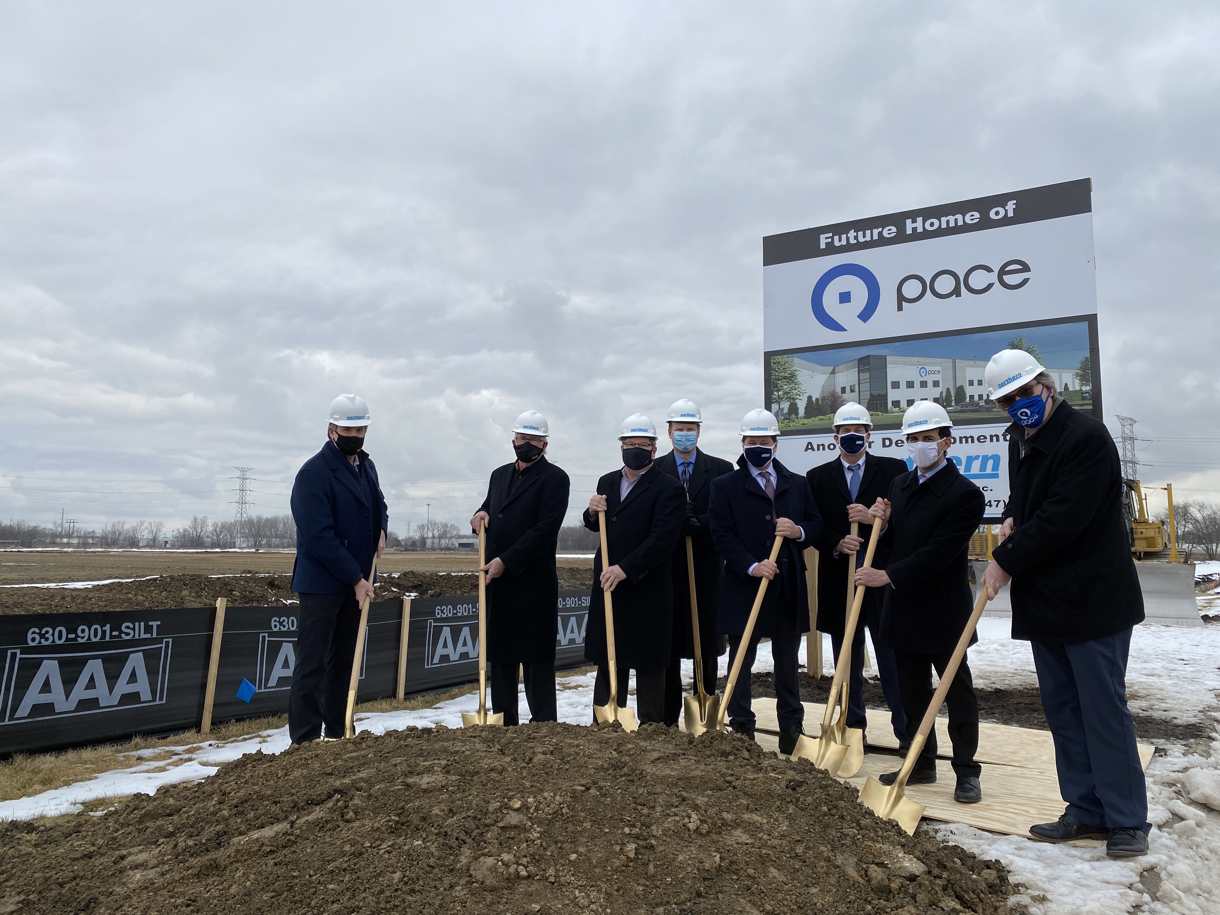 Officials with shovels and hard hats pose in front of a sign saying "future home of Pace Plainfield garage"