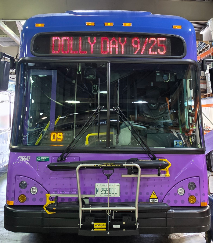 Photo of the front of a Pace Pulse bus with the digital sign above the windshield displaying the text, "Dolly Day 9/25".