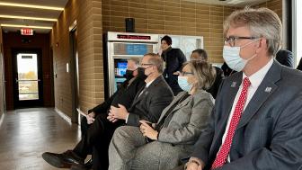 Pace officials with masks listen to a speaker inside the Plainfield park-and-ride building